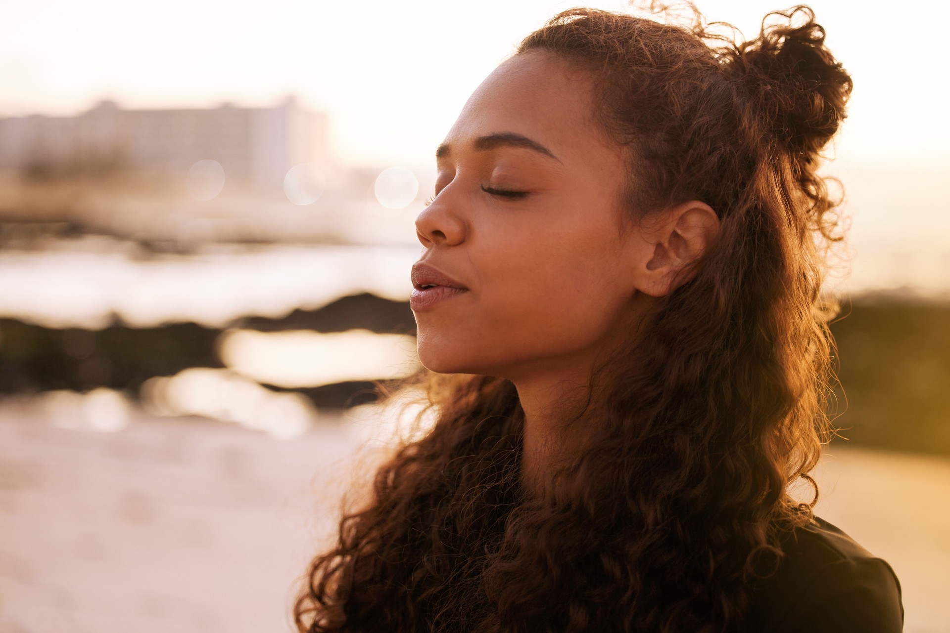 Shot of an attractive young woman sitting alone on a mat and meditating on the beach at sunset